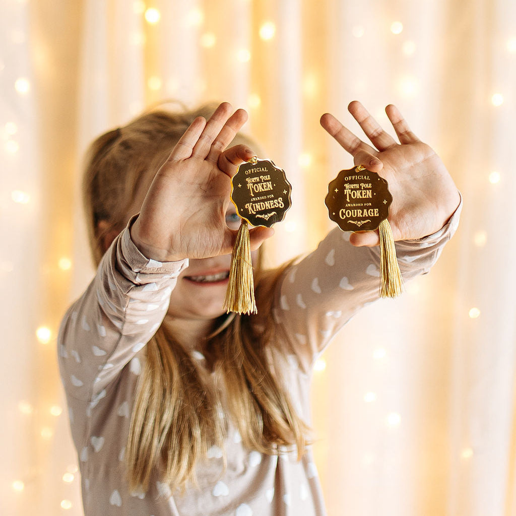 Person holding two decorative signs with tassels against a softly lit background