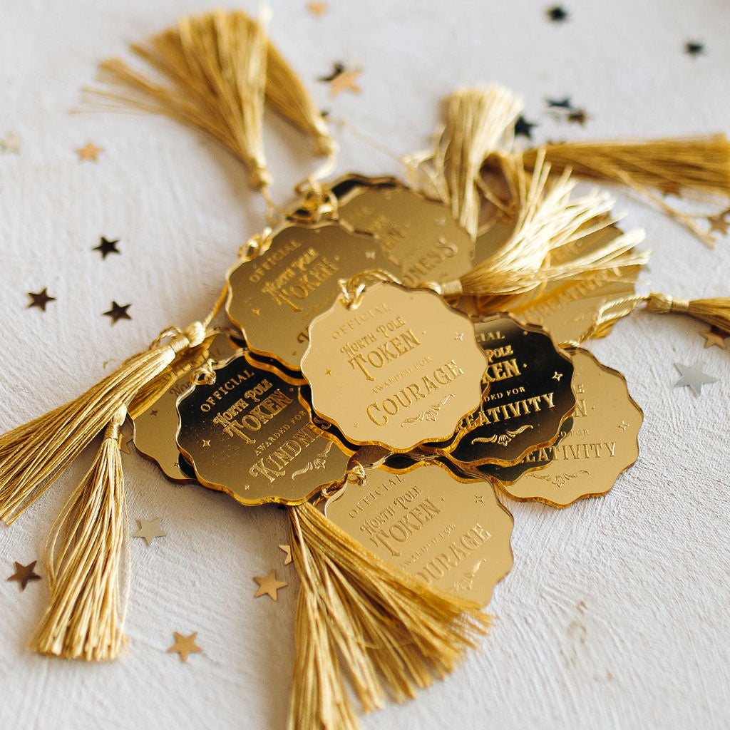 Gold North Pole tokens with tassels and engraved text 